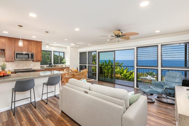 living room featuring ceiling fan, dark hardwood / wood-style flooring, and a water view