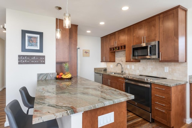 kitchen with kitchen peninsula, stainless steel appliances, light stone countertops, a breakfast bar, and sink