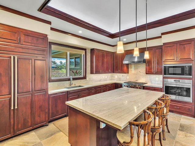 kitchen featuring sink, stainless steel oven, black microwave, a breakfast bar area, and wall chimney exhaust hood