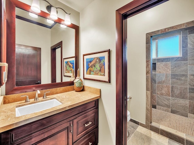 bathroom with toilet, vanity, and tiled shower