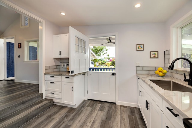 kitchen featuring light stone countertops, backsplash, sink, dark hardwood / wood-style floors, and white cabinetry