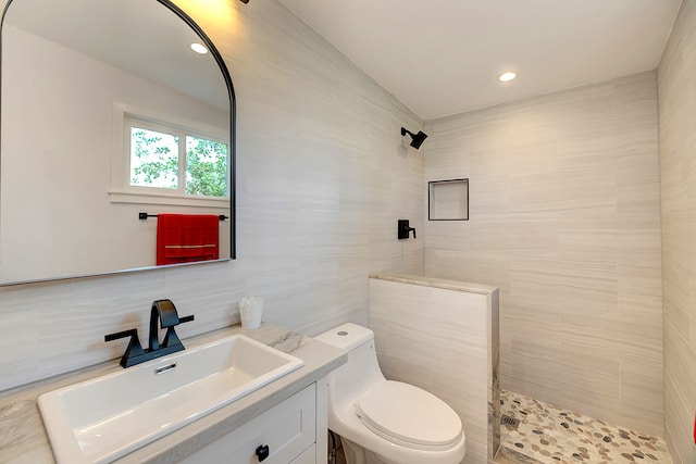 bathroom with a shower, vanity, toilet, and tile walls