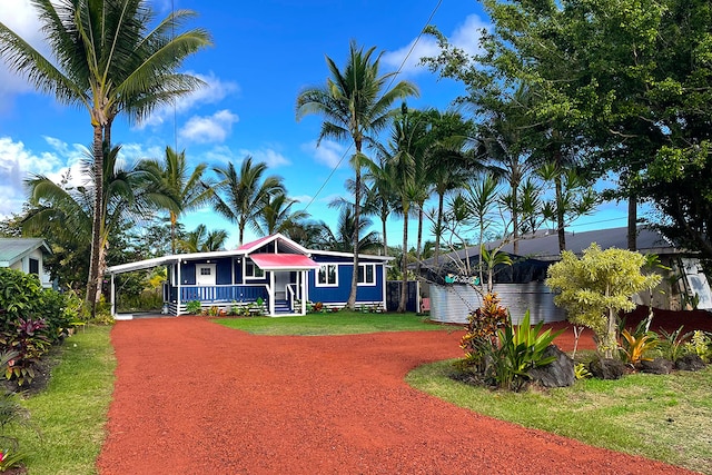 view of front facade featuring covered porch, a front lawn, and a carport