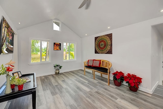 living area with ceiling fan, vaulted ceiling, and light hardwood / wood-style flooring