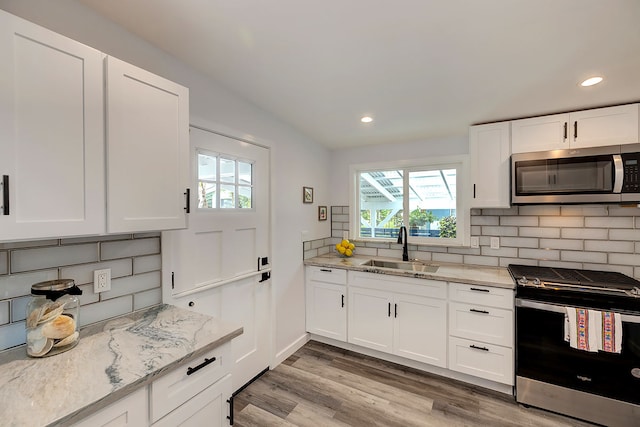 kitchen featuring light stone countertops, sink, white cabinetry, and stainless steel appliances