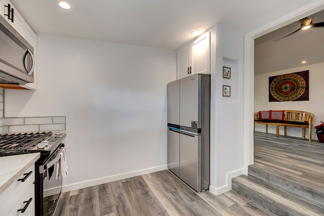 kitchen with tasteful backsplash, white cabinetry, light hardwood / wood-style flooring, and stainless steel appliances