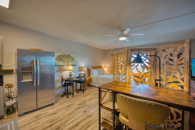 dining room featuring ceiling fan, light wood-type flooring, and a textured ceiling