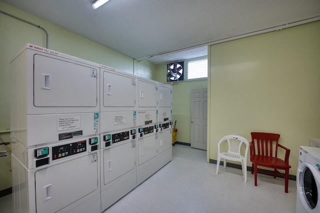 clothes washing area featuring washer and dryer, a textured ceiling, and stacked washer / drying machine