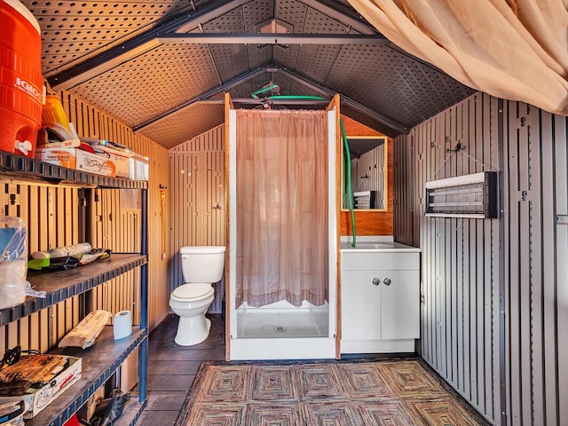 bathroom featuring lofted ceiling, toilet, and wood walls