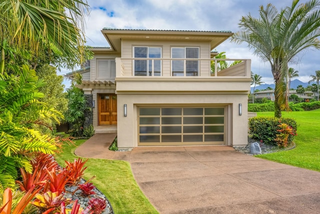 view of front of house with a front yard, a balcony, and a garage