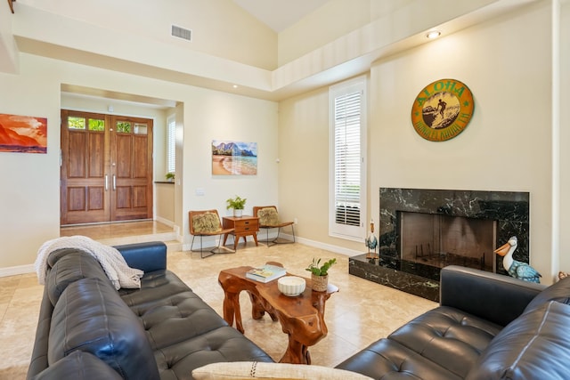 living room with a healthy amount of sunlight, light tile patterned floors, and a high end fireplace