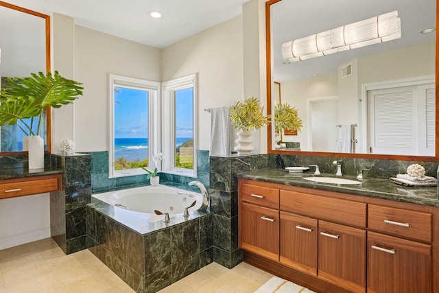 bathroom featuring tile patterned flooring, vanity, and tiled tub