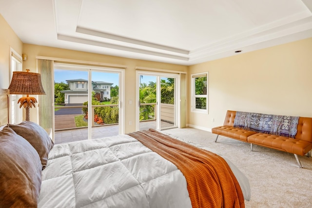 bedroom featuring access to exterior, light colored carpet, and a raised ceiling