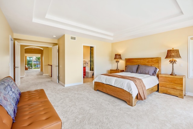 bedroom featuring carpet, a tray ceiling, and ensuite bath