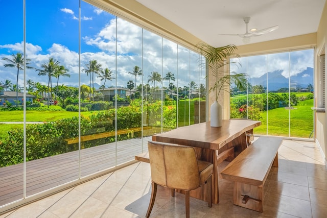 unfurnished sunroom with ceiling fan and a mountain view