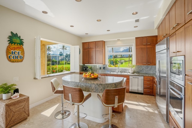 kitchen with a center island, sink, built in appliances, tasteful backsplash, and a breakfast bar area