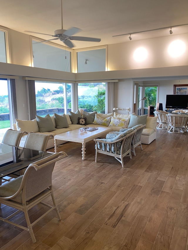 living room featuring ceiling fan, a towering ceiling, track lighting, and hardwood / wood-style floors