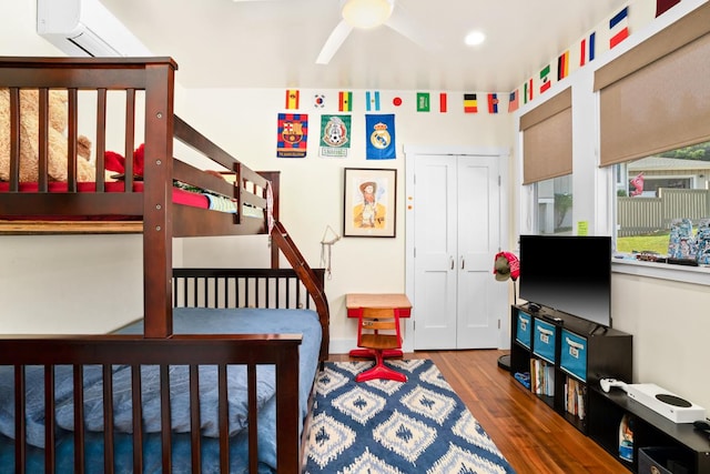 bedroom with a wall unit AC, ceiling fan, and hardwood / wood-style flooring