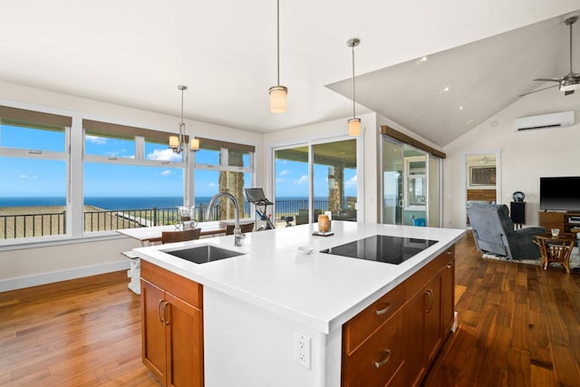 kitchen with a kitchen island with sink, sink, a water view, and hanging light fixtures