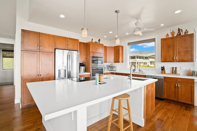 kitchen featuring pendant lighting, a kitchen breakfast bar, ceiling fan, an island with sink, and appliances with stainless steel finishes