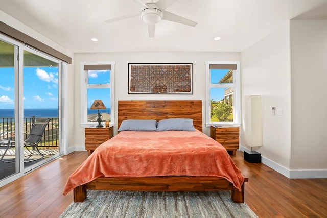 bedroom with access to exterior, ceiling fan, a water view, and hardwood / wood-style flooring