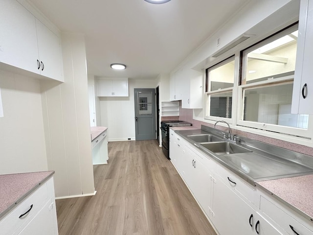 kitchen with light wood-type flooring, white cabinetry, black range with electric stovetop, and sink