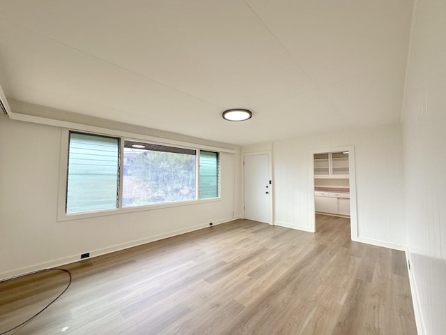 unfurnished bedroom featuring a spacious closet, a closet, and light wood-type flooring