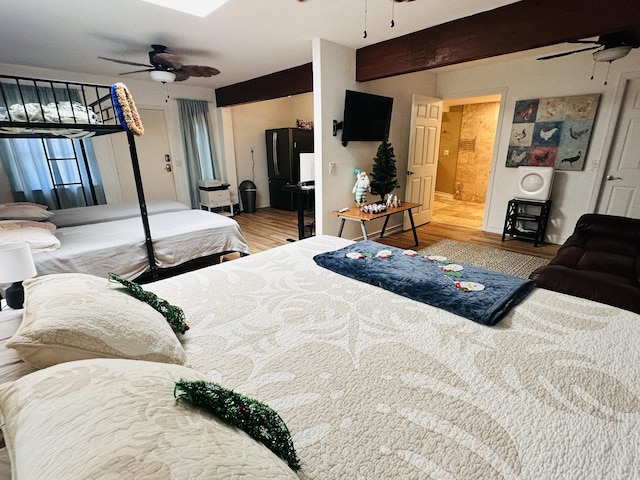 bedroom with beamed ceiling, ceiling fan, wood-type flooring, and ensuite bath