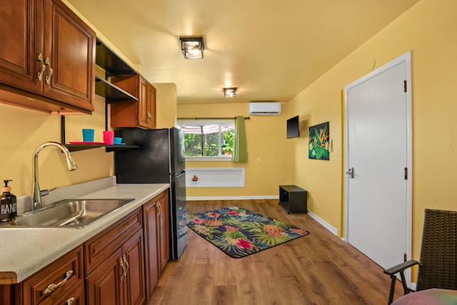 kitchen with sink, a wall mounted air conditioner, and hardwood / wood-style flooring