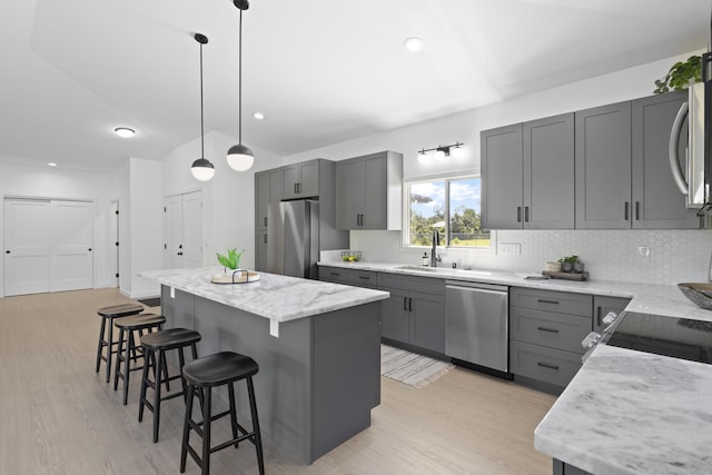 kitchen featuring decorative light fixtures, a center island, stainless steel appliances, and gray cabinetry