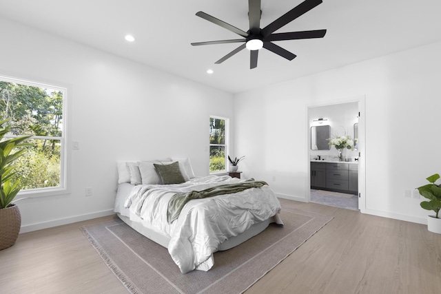 bedroom featuring multiple windows, connected bathroom, light hardwood / wood-style floors, and ceiling fan