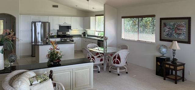 kitchen with lofted ceiling, light carpet, white cabinets, sink, and stainless steel appliances