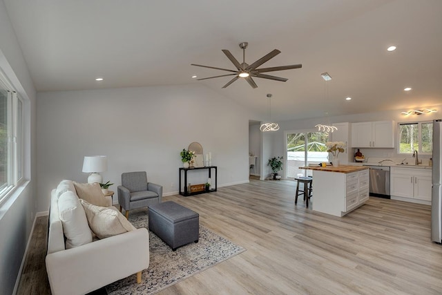 living room with ceiling fan, sink, lofted ceiling, and light hardwood / wood-style flooring