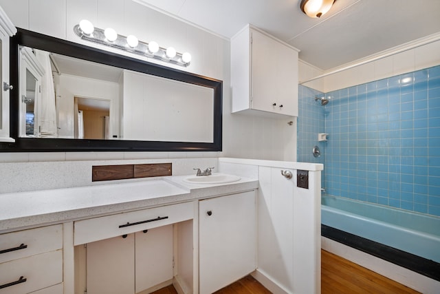 bathroom with hardwood / wood-style floors, vanity, and tiled shower / bath combo