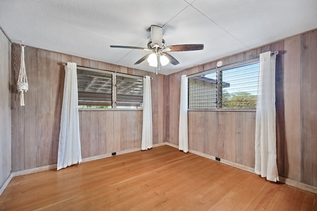 spare room with plenty of natural light, wood walls, and ceiling fan