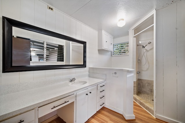 bathroom featuring tiled shower, hardwood / wood-style floors, vanity, and a textured ceiling