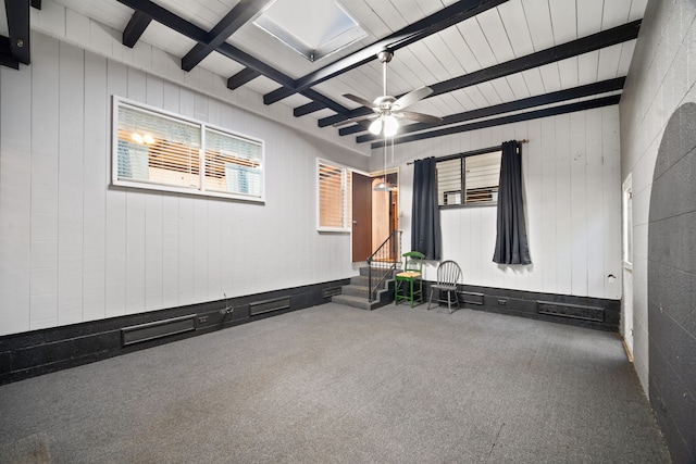 carpeted empty room featuring ceiling fan and beamed ceiling