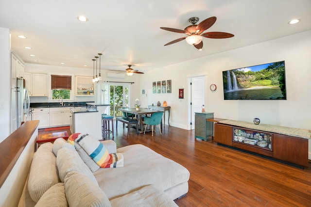 living room with dark hardwood / wood-style floors, a wall unit AC, ceiling fan, and sink