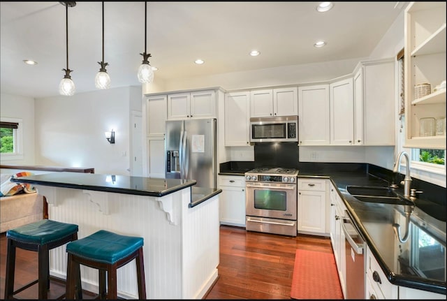 kitchen featuring white cabinets, decorative light fixtures, stainless steel appliances, and sink