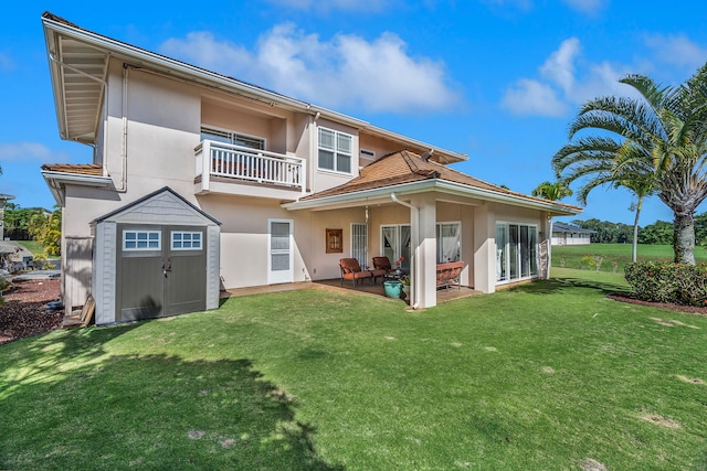 back of property featuring a yard, a patio, a balcony, and a storage shed