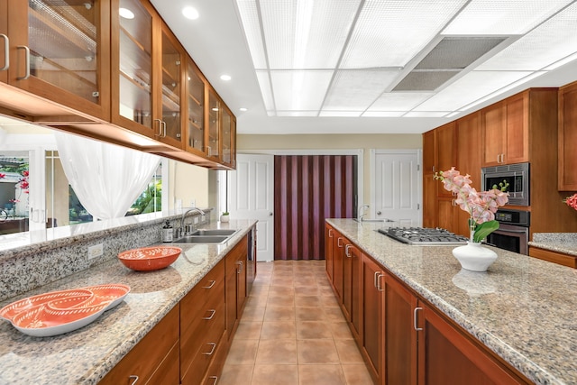 kitchen with light tile patterned flooring, sink, light stone countertops, and stainless steel appliances