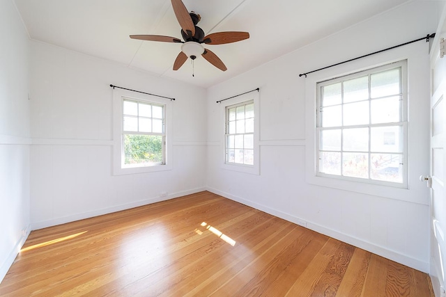 spare room with ceiling fan, a wealth of natural light, and light wood-type flooring