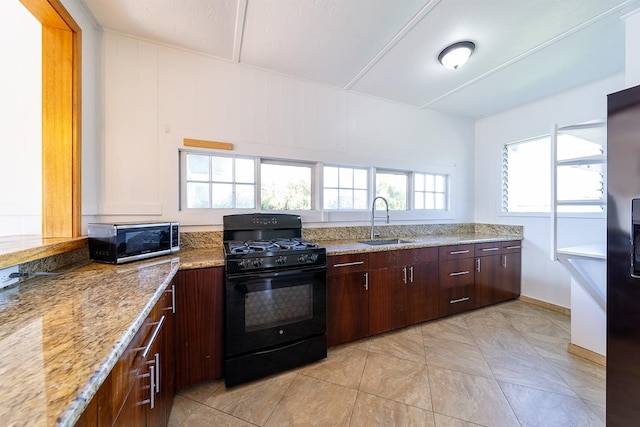 kitchen featuring sink, light tile patterned floors, light stone counters, dark brown cabinetry, and black range with gas stovetop