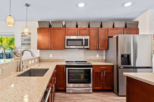 kitchen with sink, stainless steel appliances, light stone counters, pendant lighting, and decorative backsplash