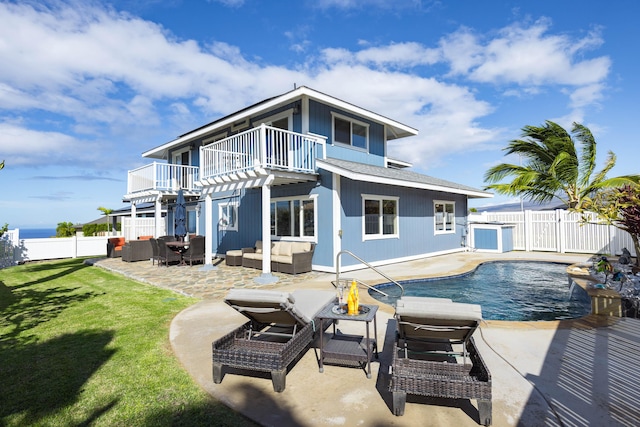 back of property with a patio, a yard, a balcony, a fenced in pool, and an outdoor living space