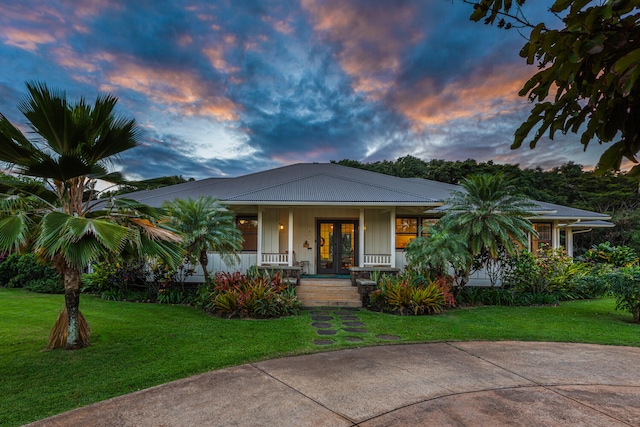 view of front of house featuring french doors, a porch, and a yard