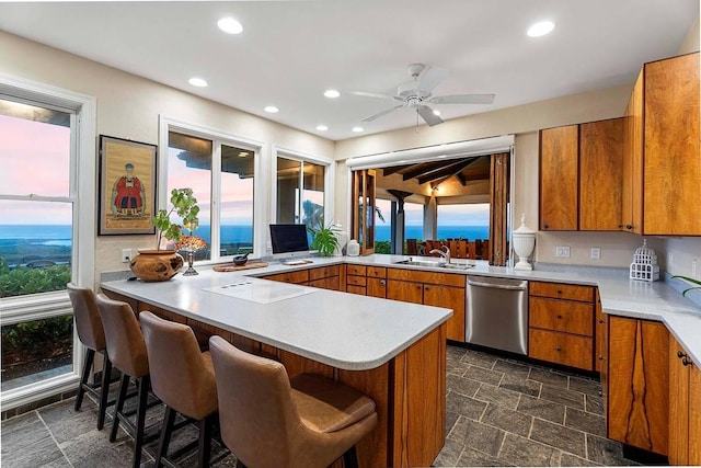 kitchen featuring kitchen peninsula, stainless steel dishwasher, a breakfast bar, ceiling fan, and sink