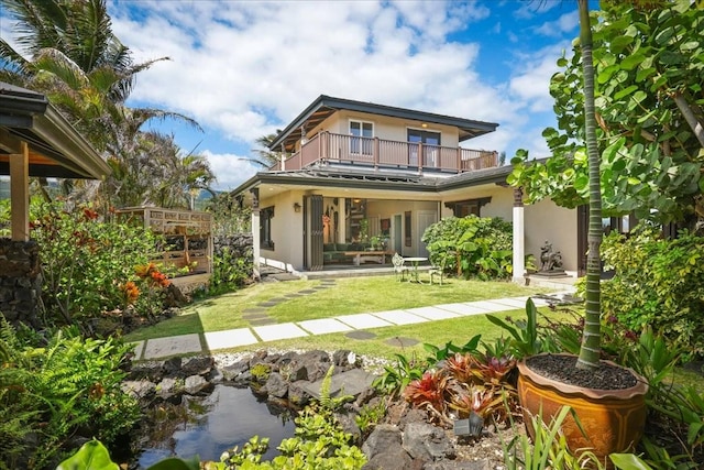 rear view of property featuring a lawn and a balcony