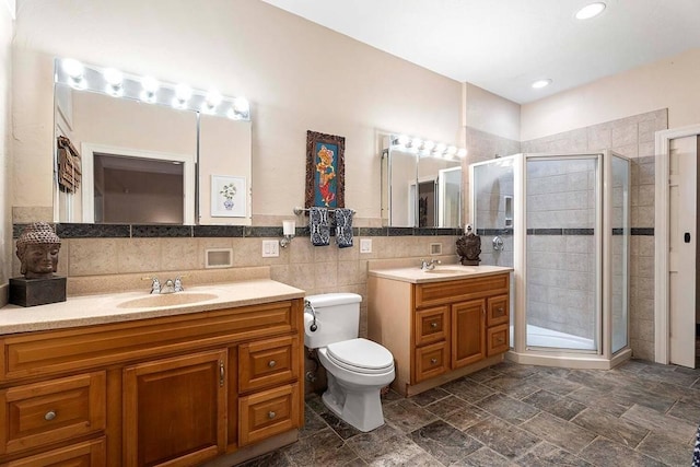 bathroom featuring toilet, vanity, tile walls, and walk in shower