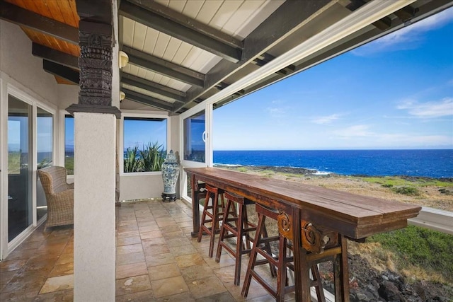 view of patio / terrace featuring a view of the beach, a bar, and a water view